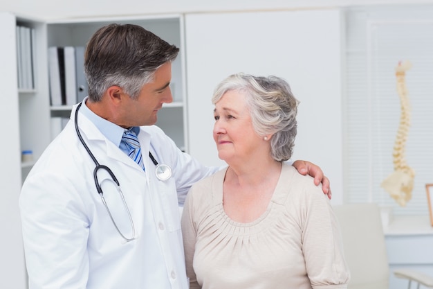 Doctor consoling senior woman in clinic