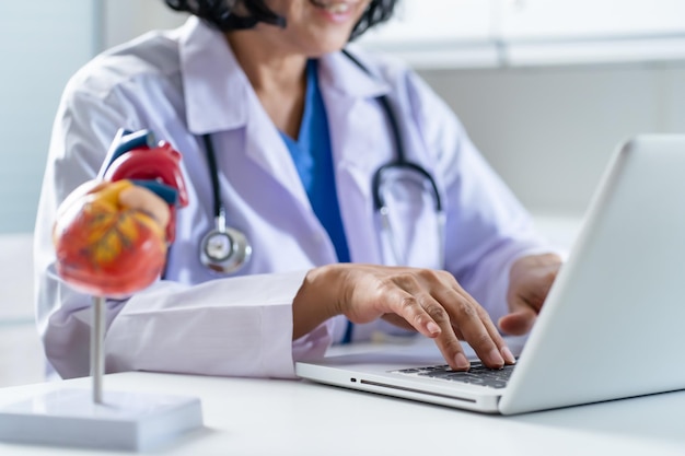 Foto il medico consulta il paziente sul laptop con il modello anatomico del cuore umano il cardiologo supporta il cuore appuntamento medico online