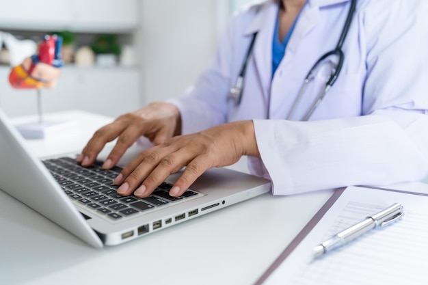 Photo doctor consult patient on laptop with anatomical model of human heart cardiologist supports