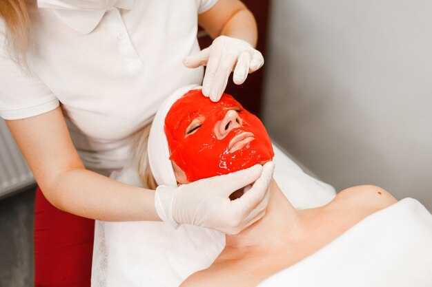 Doctor cosmetologist applies face mask to patient