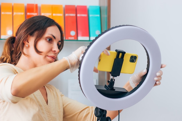 Doctor cosmetologist blogger shoots a video plot vlog on a phone with a ring lamp in the office