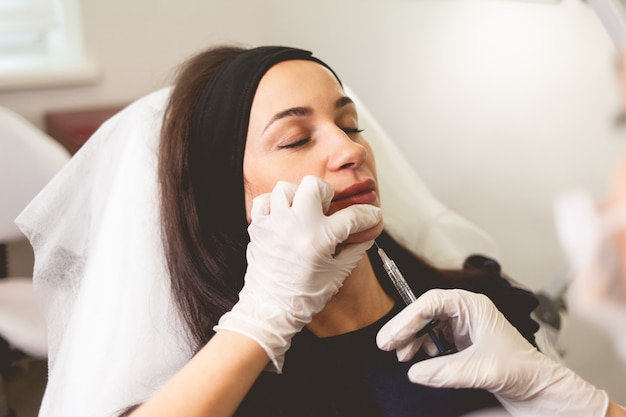 Doctor cosmetologist gives a chin injection for patient