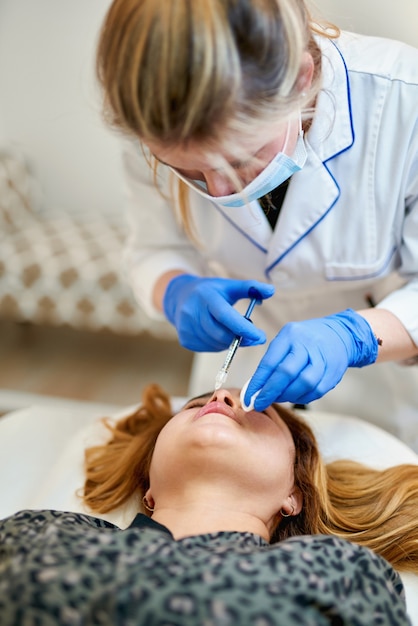 Il cosmetologo medico fa la procedura di aumento delle labbra di una bella donna in un salone di bellezza