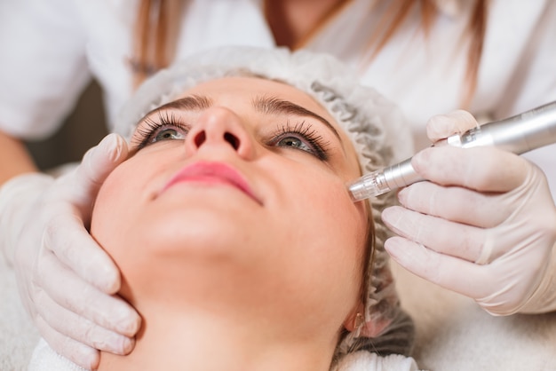 The doctor-cosmetologist makes a procedure of ultrasound cleaning of the facial skin