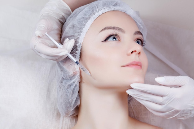 The doctor cosmetologist makes the Rejuvenating facial injections procedure in a beauty salon