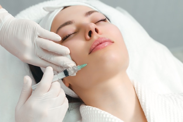 The doctor cosmetologist makes the rejuvenating facial injections procedure for tightening and