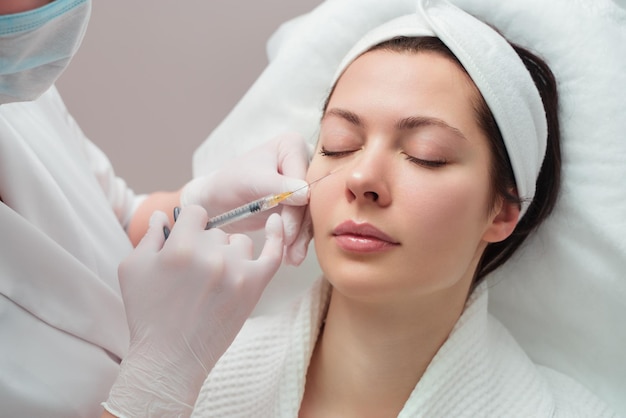 The doctor cosmetologist makes the rejuvenating facial injections procedure for tightening and