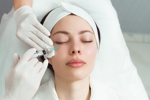 The doctor cosmetologist makes the rejuvenating facial injections procedure for tightening and