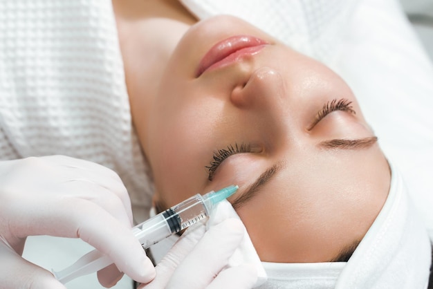 The doctor cosmetologist makes the rejuvenating facial injections procedure for tightening and