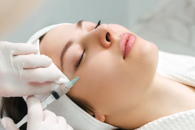 The doctor cosmetologist makes the rejuvenating facial injections procedure for tightening and