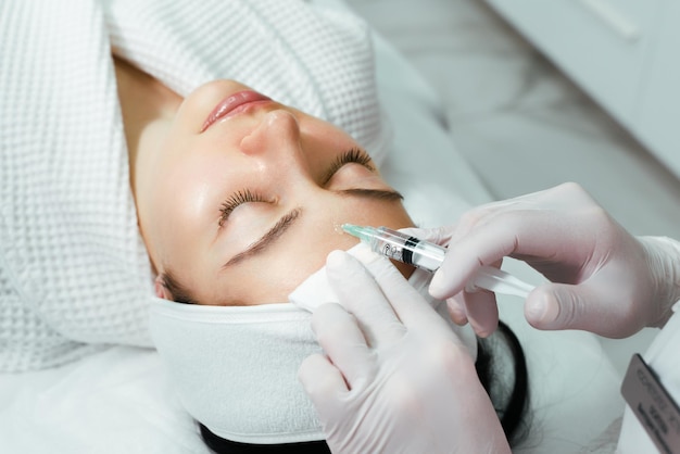 The doctor cosmetologist makes the rejuvenating facial injections procedure for tightening and