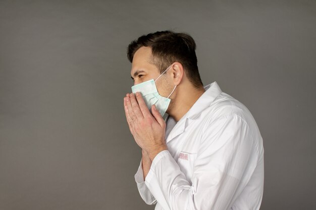 врач кашляет и надевает маску для защиты от коронавируса