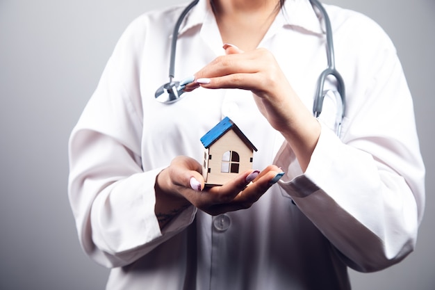 Doctor covers house model with her hands