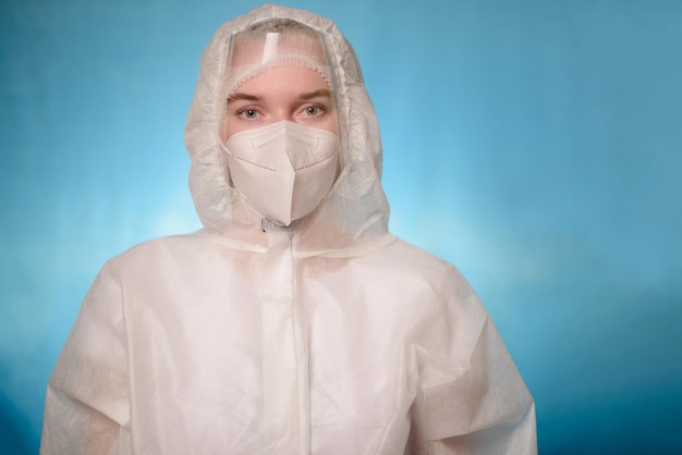 A doctor in a Covid 19 protective suit stands and looks into the frame