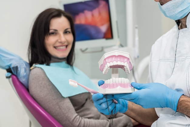 Doctor demonstrating jaw model over patient background