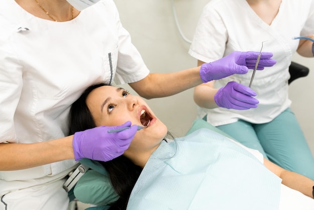 Dentista medico che fa esame di stomatologia medica per paziente donna utilizzando strumenti professionali