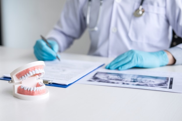 doctor or dentist working with patient tooth x-ray film, model and equipment used in the treatment