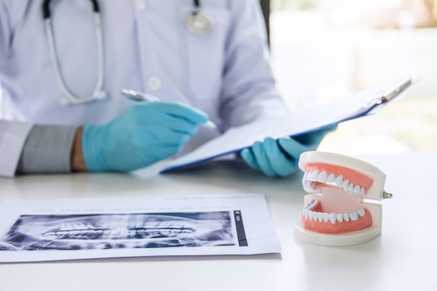 doctor or dentist working with report and patient tooth x-ray film, model and equipment used in the treatment and analysis teeth disease of dental