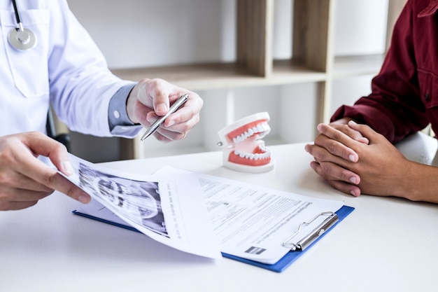 Rapporto di scrittura del medico o del dentista che lavora con il modello del film dei raggi x del dente