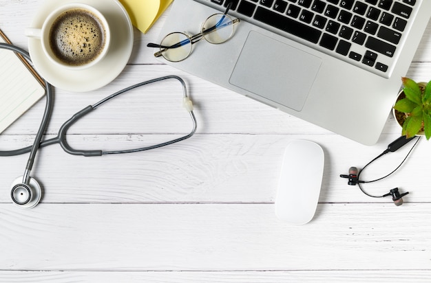 Foto tavola di legno del medico con stetoscopio e notebook