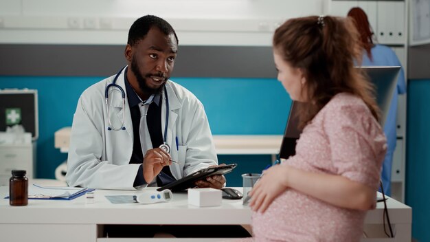 Photo doctor discussing with pregnant woman at clinic