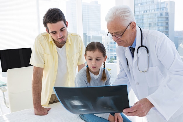 Doctor discussing x-ray report with father and daughter