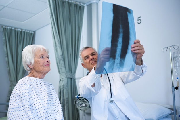 Medico che discute il rapporto dei raggi x con il paziente anziano