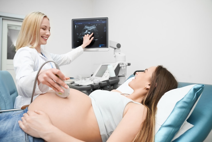 Photo doctor doing ultrasound exam of pregnant woman's abdomen.