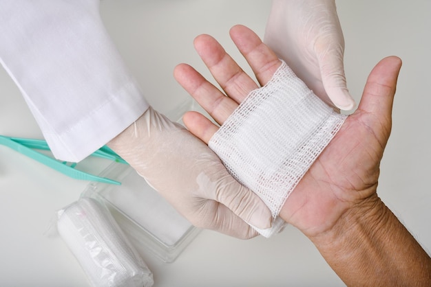 Foto medico che esegue la cura della medicazione e il bendaggio della mano del paziente trattamento chirurgico della mano l'infermiera cura la lesione del dito del paziente in ospedale