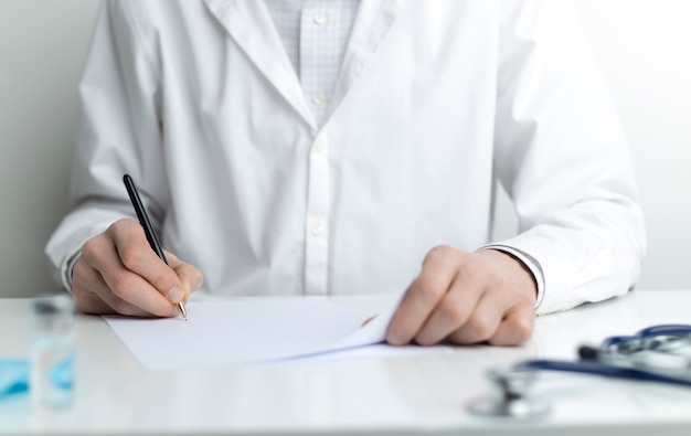 Doctor in a dressing gown writes a prescription at the workplace