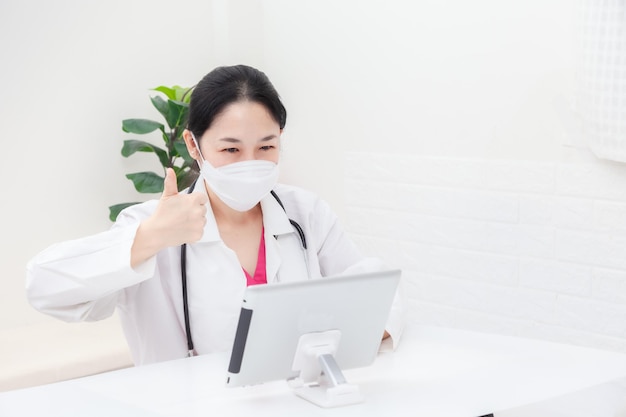 Doctor examine the patient via video call. Asian female doctor examines patients treatment, explains medicines and gives encouragement online. health care and prevention COVID-19 strategy concept