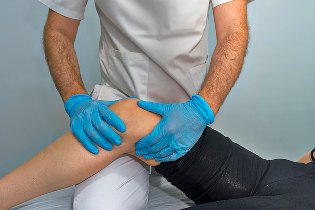 Doctor examines the knee of a girl.