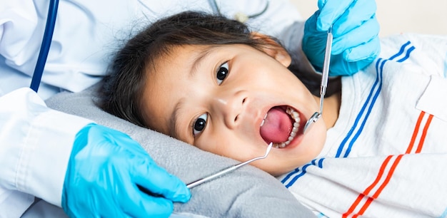 Doctor examines oral cavity of little child uses mouth mirror to checking teeth cavity