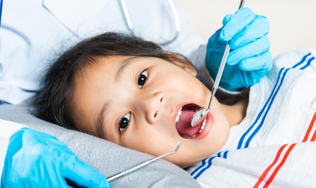 Doctor examines oral cavity of little child uses mouth mirror to checking teeth cavity