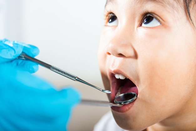 Doctor examines oral cavity of little child uses mouth mirror to checking teeth cavity