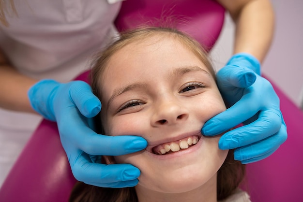 Doctor examines oral cavity of small baby girl uses an oral mirror to check cavity of teeth