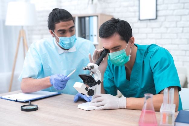 Doctor examines patient's blood sample in a microscope.