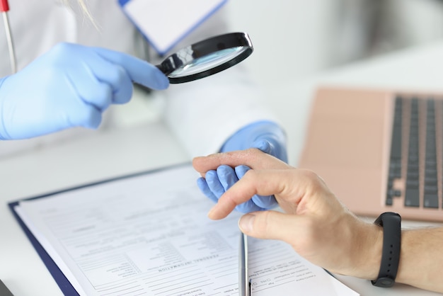 Doctor examines patient's peeling finger through magnifying glass. Skin problems and solutions concept