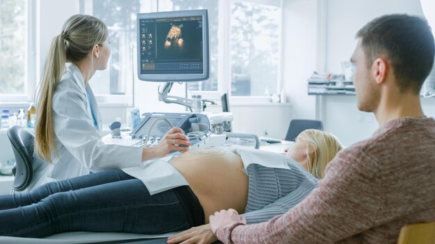 A doctor examines a pregnant woman at a doctor's office.