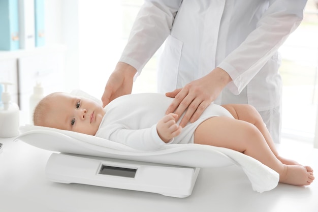 Doctor examining baby on scales in room