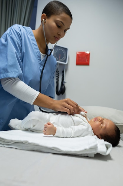 Doctor examining baby with stethoscope in medical examination room