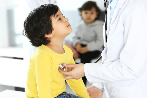 Doctor examining a child patient by stethoscope Cute arab boy at physician appointment Medicine and healthcare concept