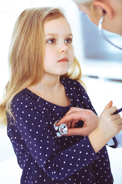 Doctor examining a child patient by stethoscope. Cute baby girl at physician appointment. Medicine concept. Toned photo