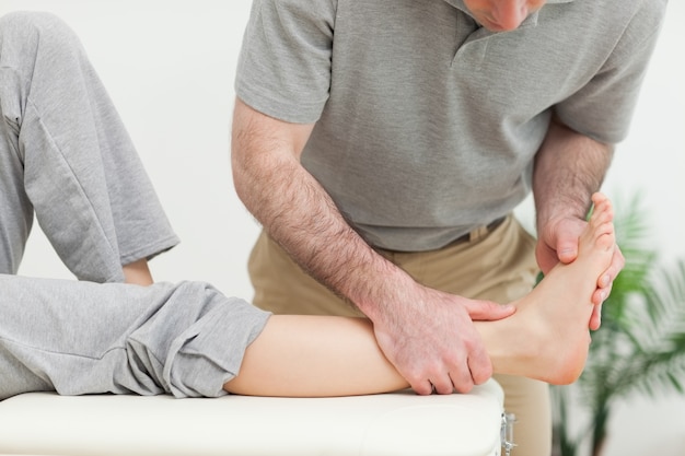 Doctor examining the foot of a woman while standing