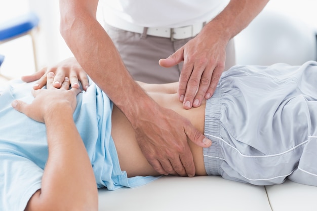 Doctor examining his patient stomach 