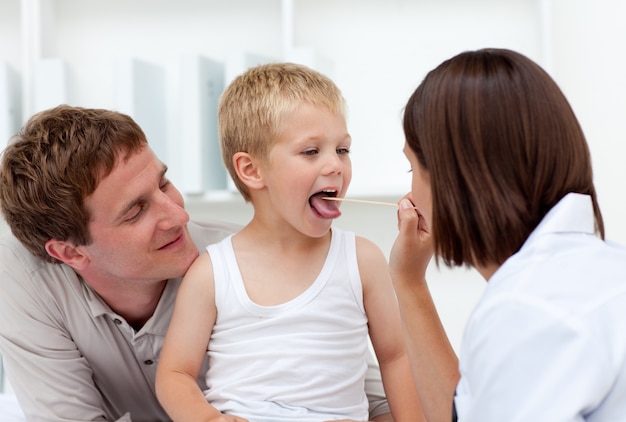 Doctor examining a little boy with his father in tow 