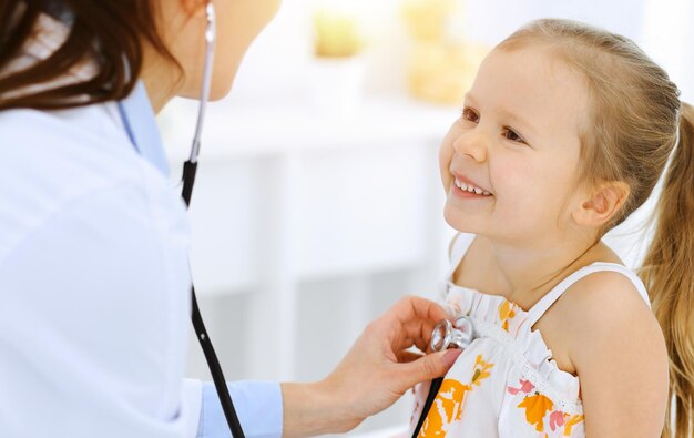 doctor examining a little girl by stethoscope. happy smiling child patient at usual medical inspection. medicine and healthcare concepts.