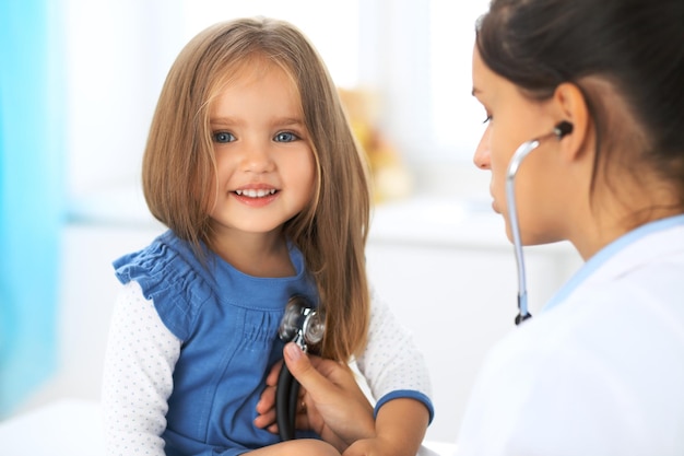 Доктор осматривает маленькую девочку с помощью стетоскопа