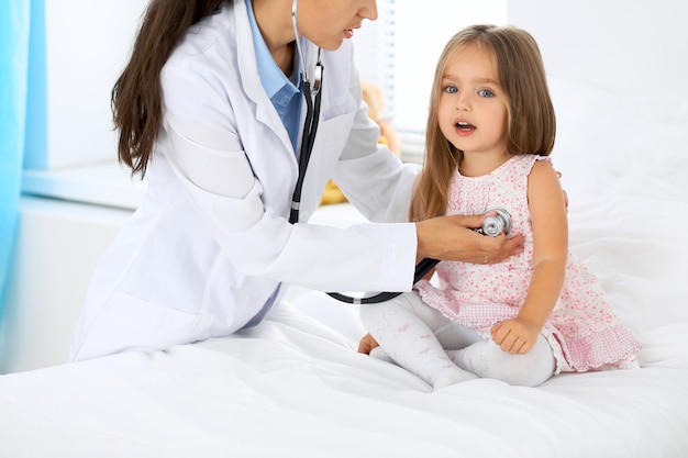 Доктор осматривает маленькую девочку с помощью стетоскопа