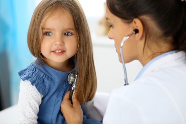 Доктор осматривает маленькую девочку с помощью стетоскопа.